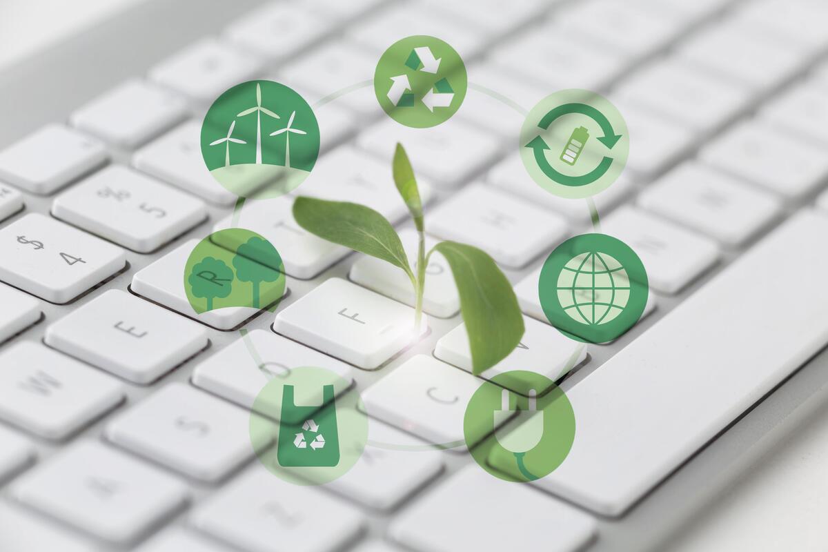 Green plant sprouting from a white keyboard surrounded by eco-friendly icons representing sustainability, recycling, renewable energy, and digital environmental impact
