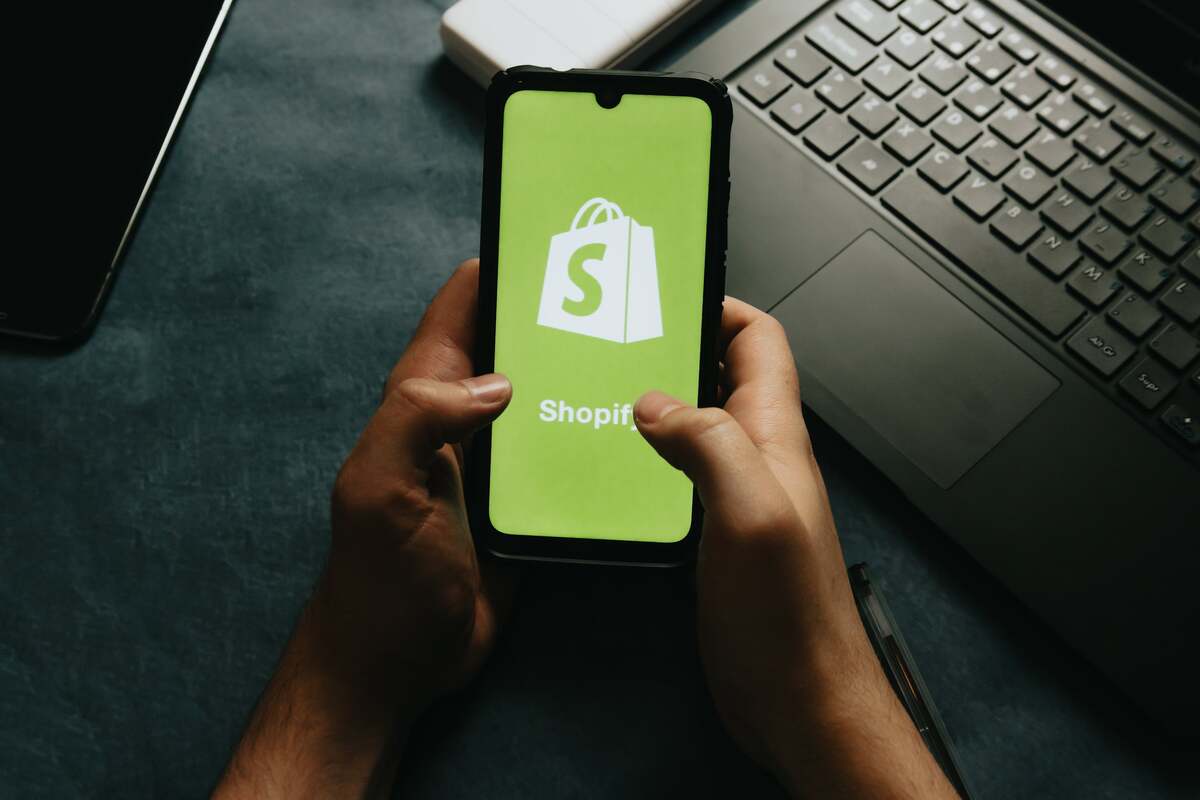 Person holding a smartphone displaying the Spotify logo on the screen.