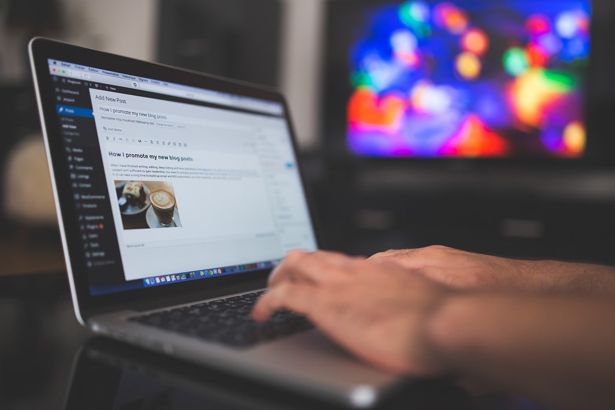 Hands typing on a laptop with a screen showing an open wordpress editing page