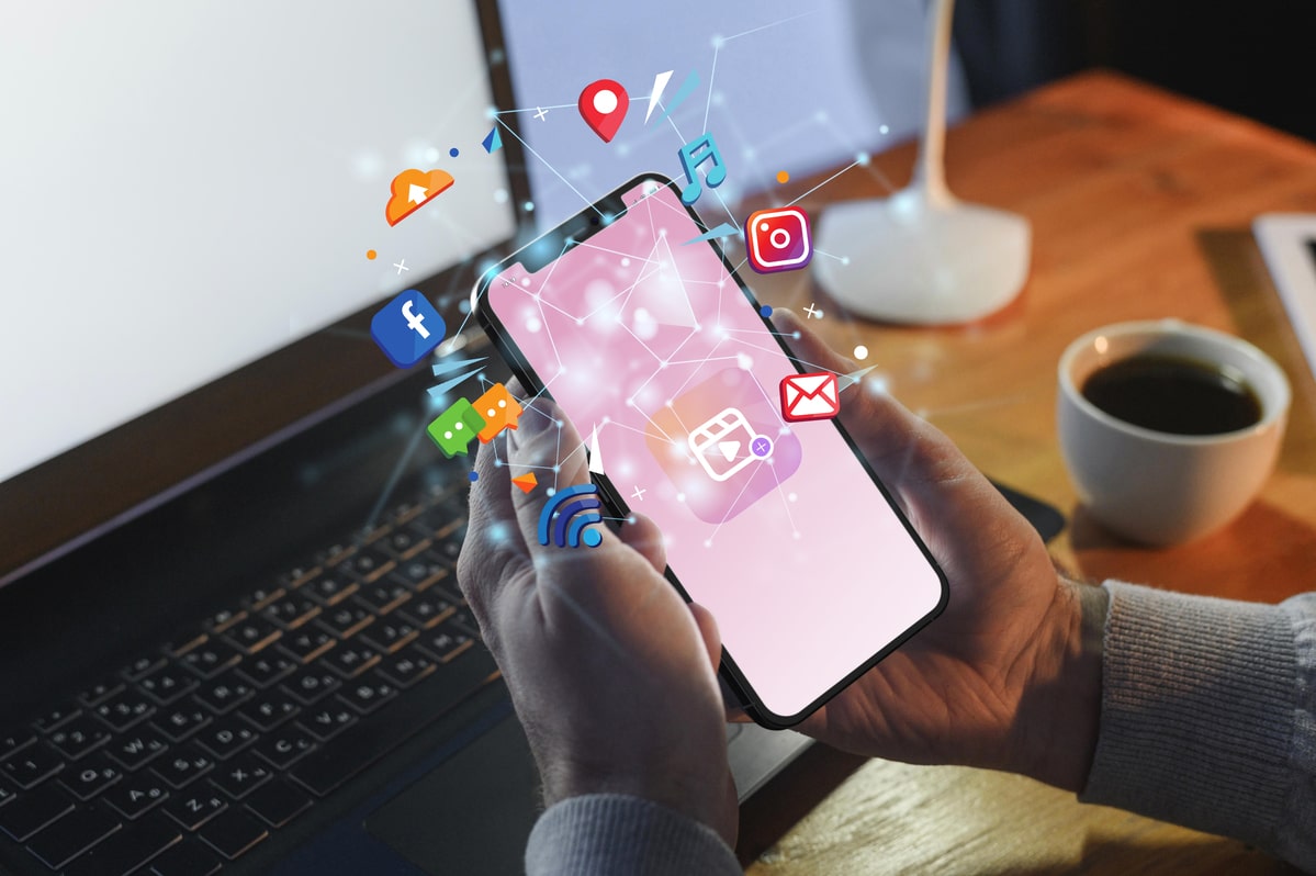 hands holding-smartphone with illustrated social media floating in a circle around the screen
