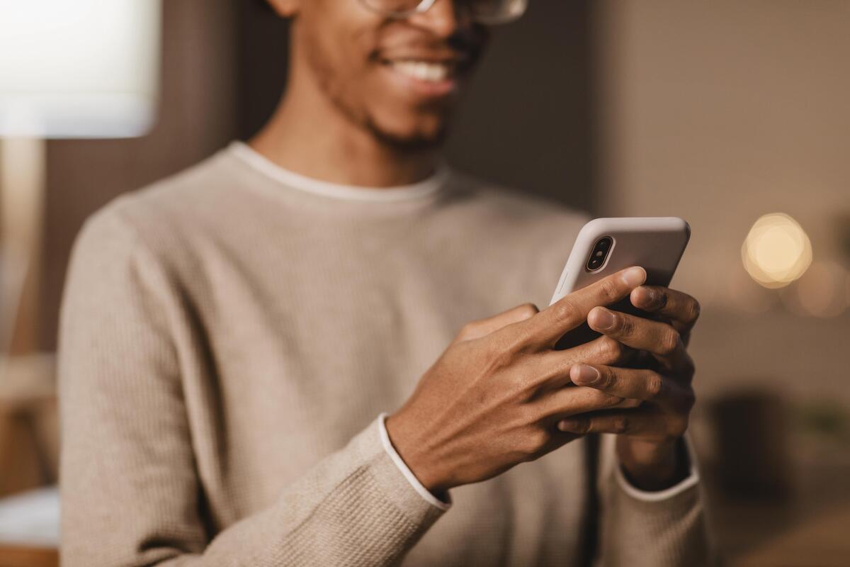 man smiling while holding a modern smartphone