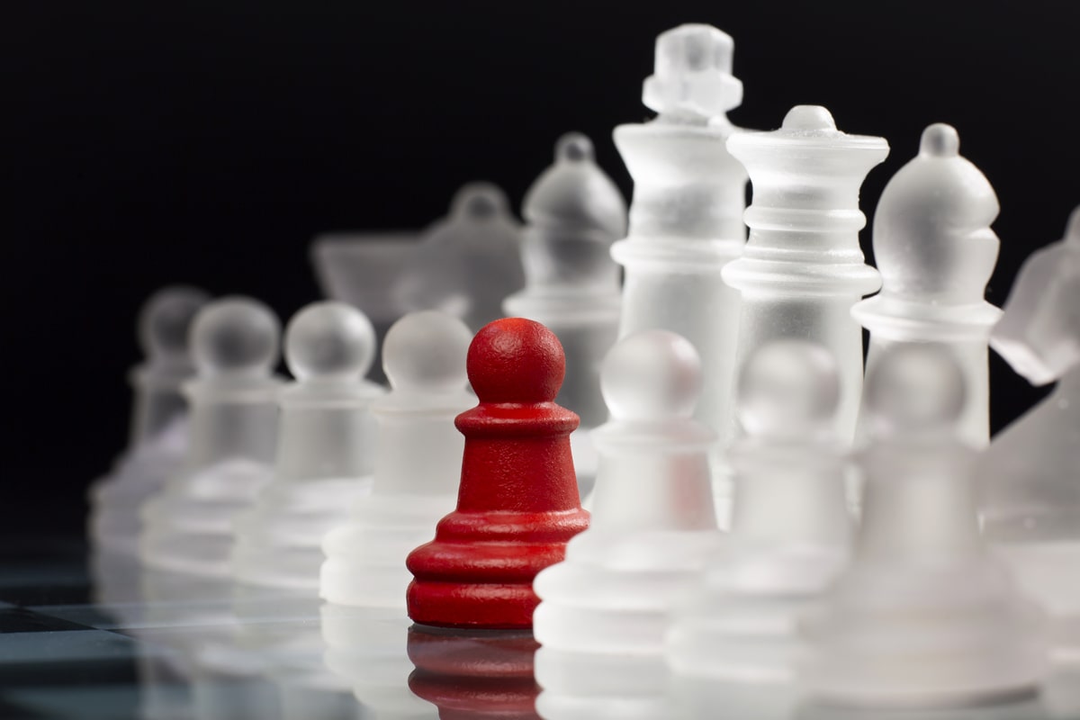 A line of chess pawns with one in the color red, standing out in the middle
