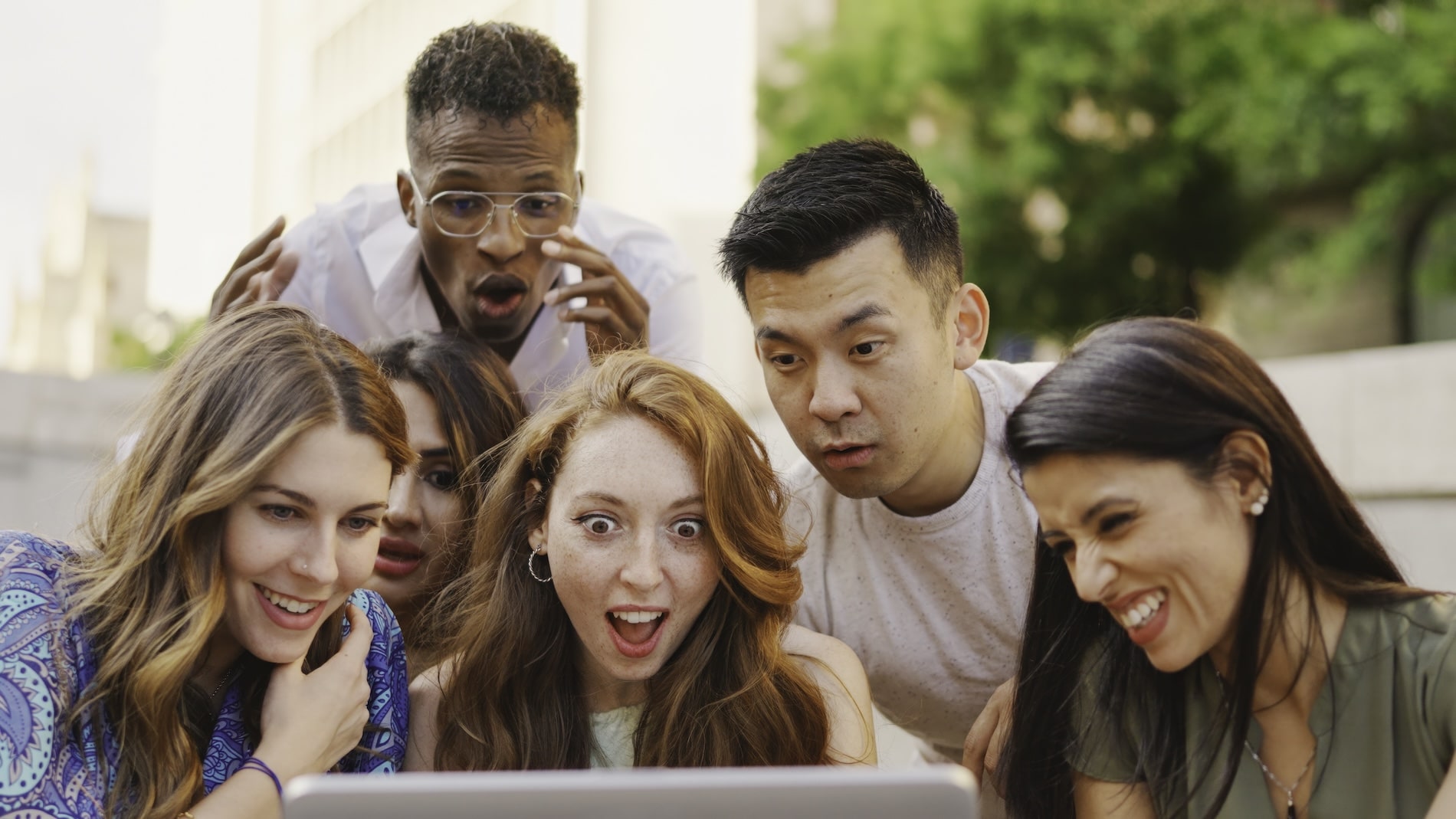 Diverse group of people reacting to a website design on a laptop screen.